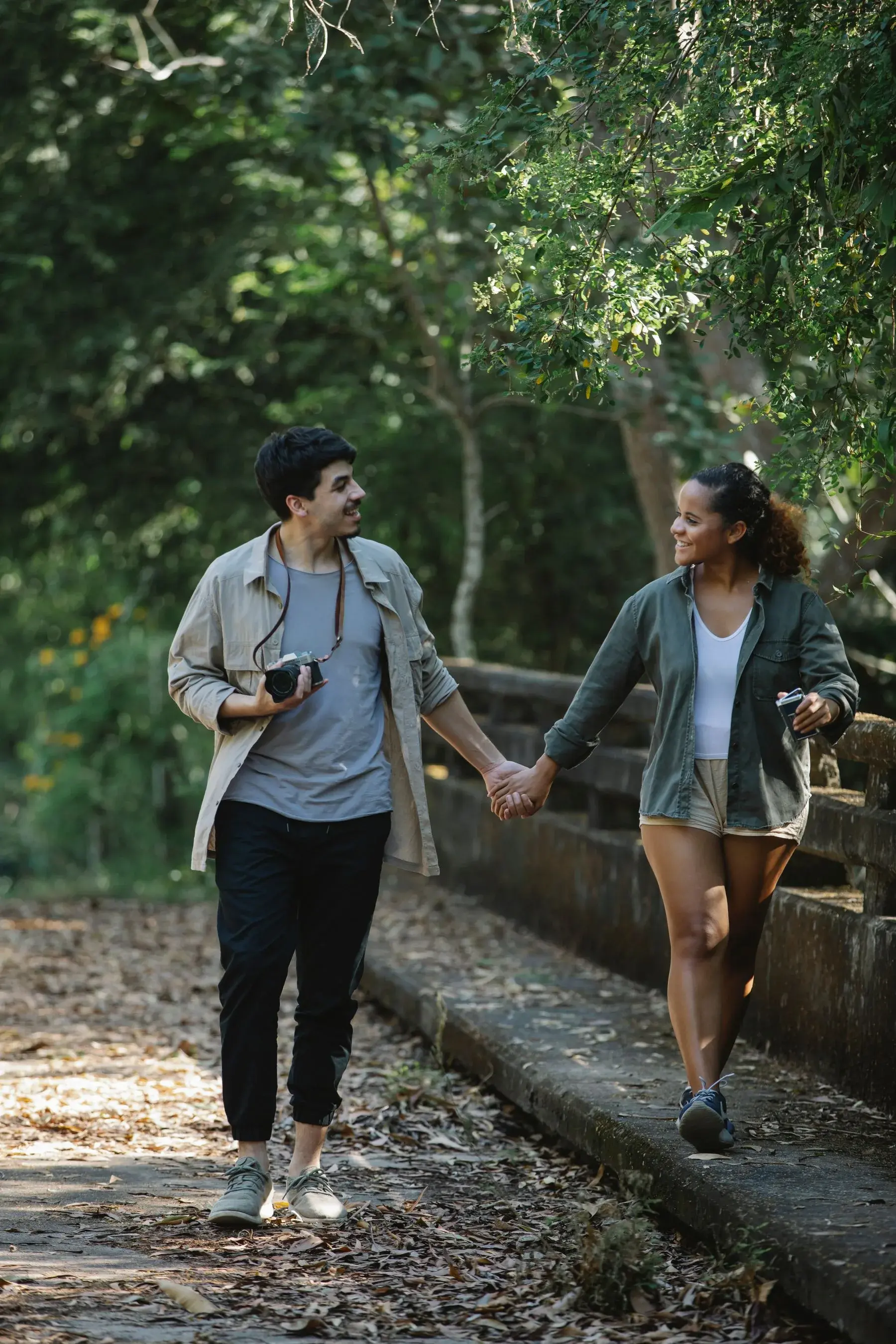 A couple walking together along a sunny tree-lined park path